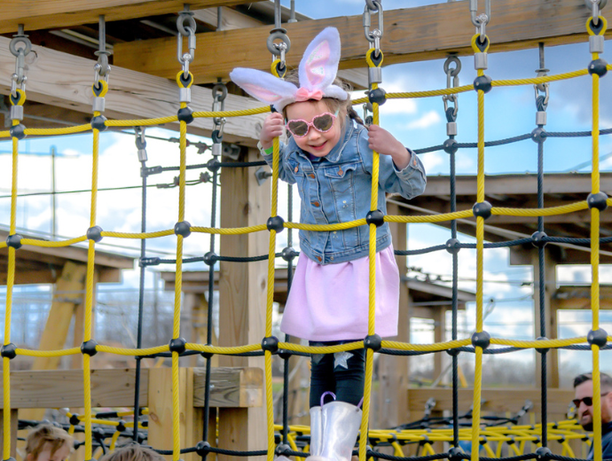 Child wearing bunny ears on a playground structure